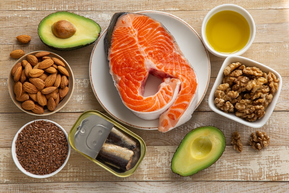 gesunde fette lebensmittel omega 3 lebensmittel lachs avocado anti entzündliche ernährung keto lebensmittel gesunde ernährung nüsse samen avocado halbiert lachsfilet roh olivenöl chiasamen mandeln walnüsse sardinen dose gesunde ernährungsplan